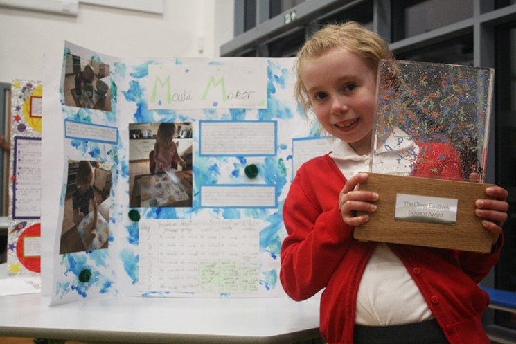 child with a trophy in front of a science display