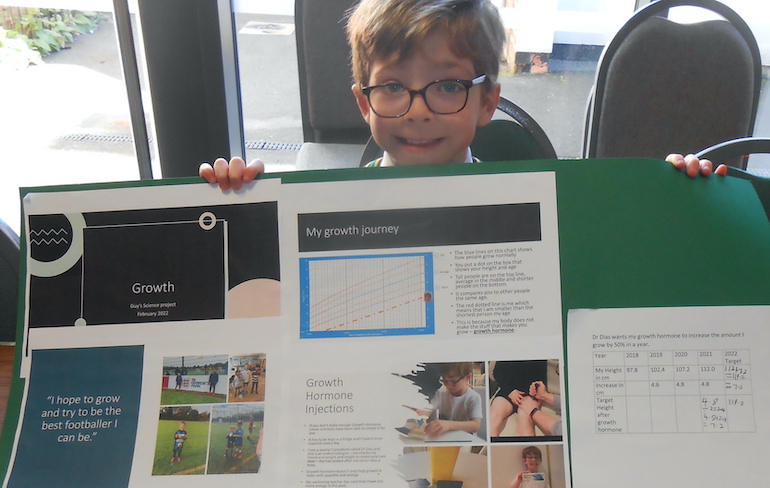 A boy holds up his investigation presentation