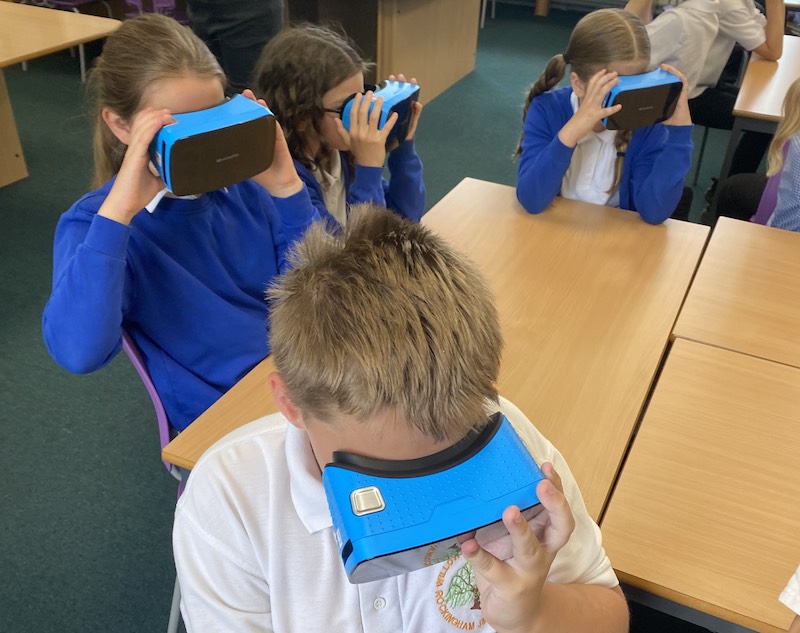 four children seated around a table with VR headsets on