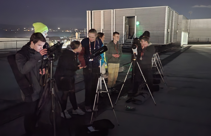 Astronomy Enrichment group on the college rooftop looking through their telescope, watching the stars.